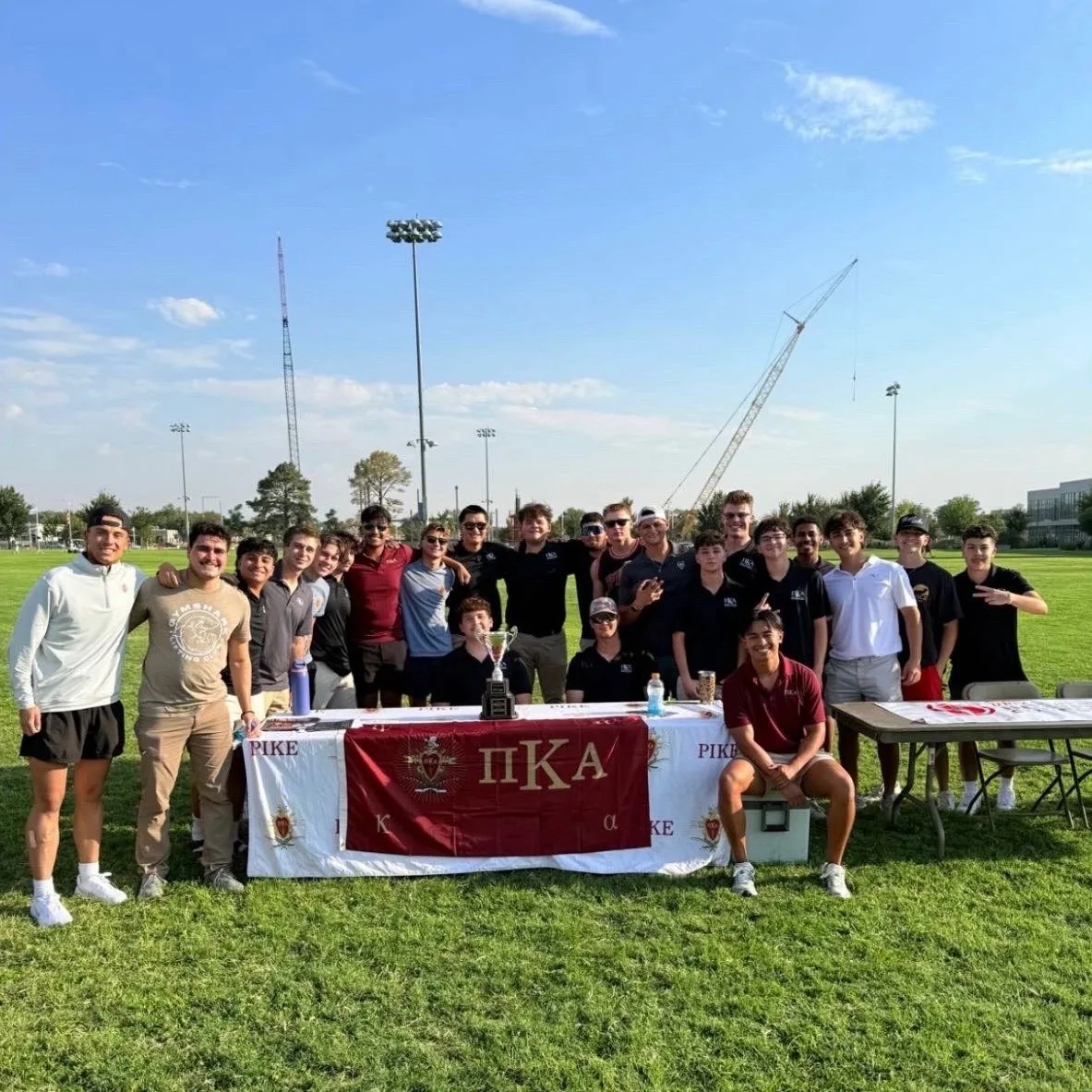 PIKE BROTHERS GATHERING OUTDOORS BEHIND A PIKE BANNER.