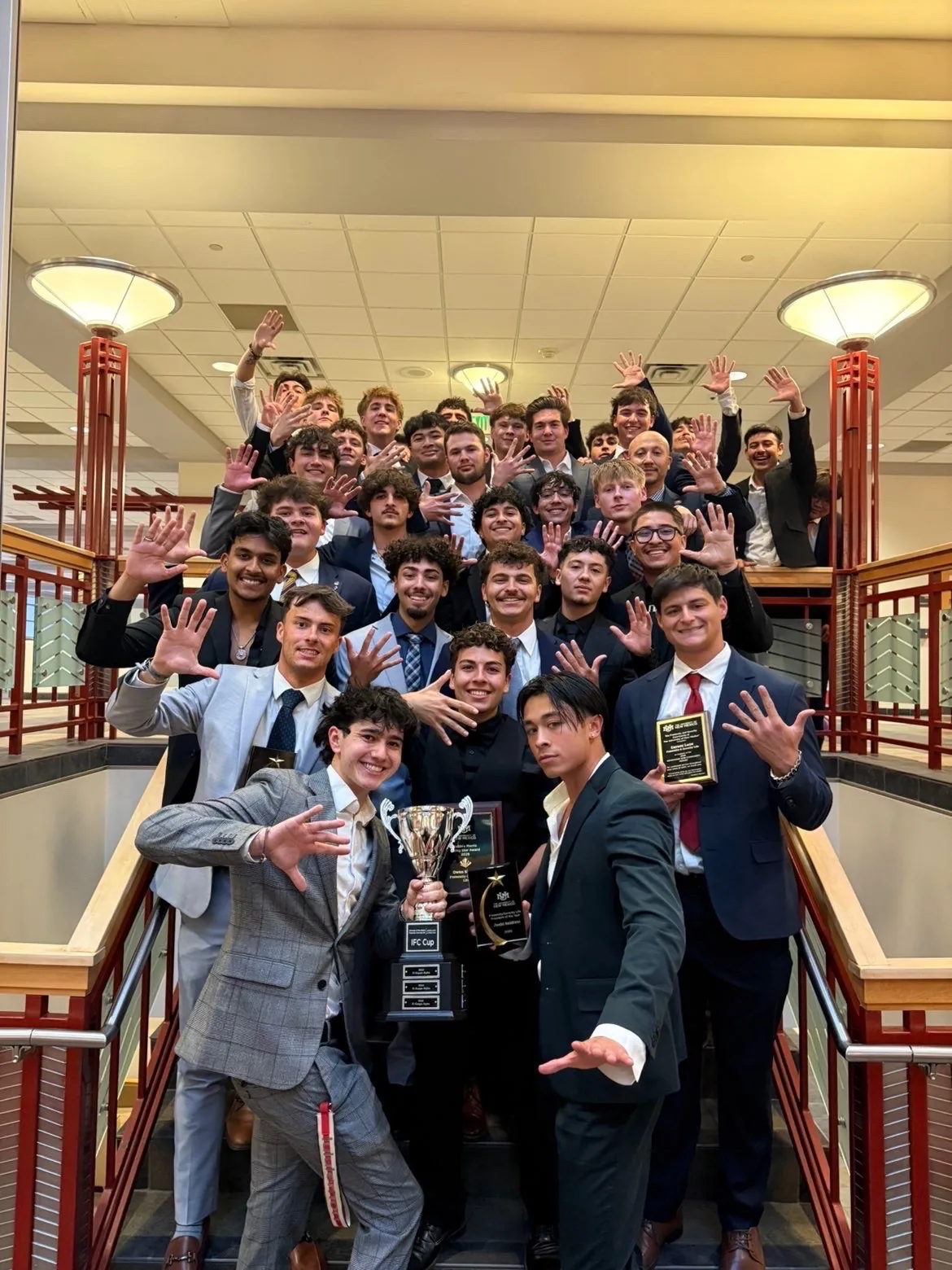 BROTHERS GATHERED WITH AWARDS AT A CAMPUS CELEBRATION.